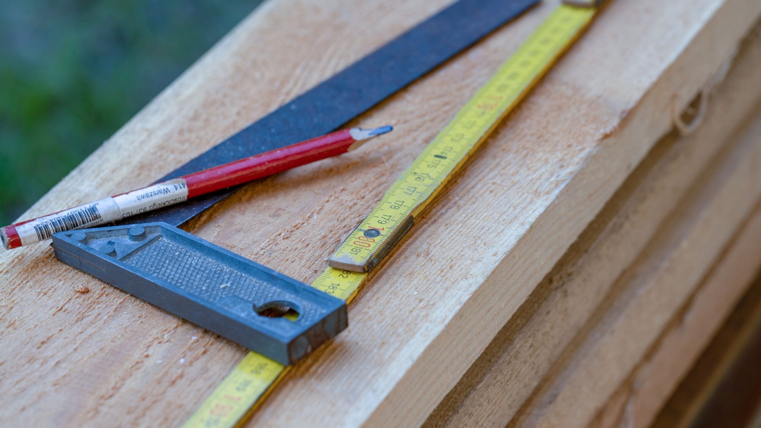 Carpenter's tools including a tape measure and pencil on a wooden beam