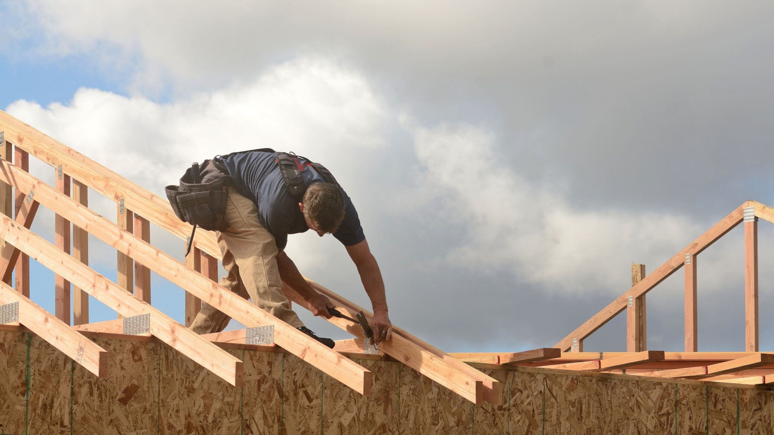 Roofer installing wooden rafters on a house under construction