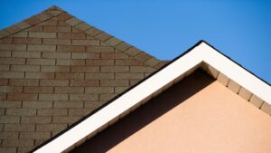 Steep shingle roof with clean white trim against a clear blue sky